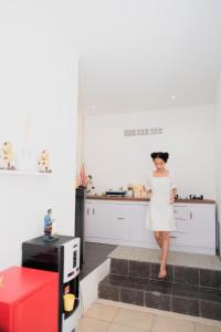 a woman in a white dress standing in a kitchen at Roemah Renjana Yogyakarta in Timuran