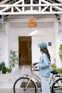 a woman standing next to a bike in front of a building at Roemah Renjana Yogyakarta in Timuran