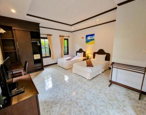 een woonkamer met 2 bedden en een televisie bij Jasmin Resort - SHA Plus in Khao Lak