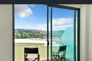 a balcony with two chairs and a large glass window at Self contained in city with on site restaurant, gym & parking in Launceston