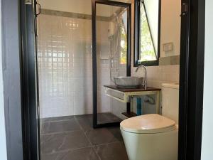 uma casa de banho com um lavatório, um WC e um espelho. em Kunna House em Ko Yao Noi