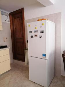 una nevera blanca en una cocina junto a una puerta en Chez Papi - A 5 min da piste da Sci e Stazione CIR VDA AO 0013 en Aosta