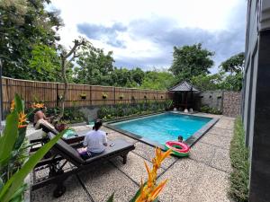 a group of people sitting around a swimming pool at Green Hill Inn in Jimbaran