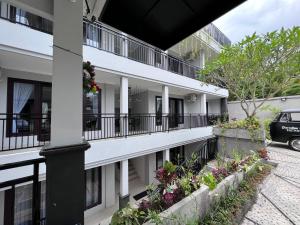 a white building with balconies and flowers on it at Green Hill Inn in Jimbaran