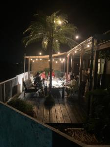a group of people sitting on a deck at night at ゲストハウスナゼ in Amami
