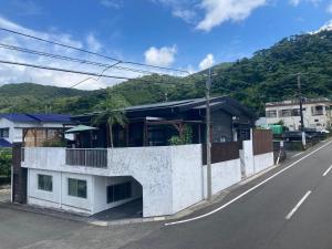 a white building on the side of a road at ゲストハウスナゼ in Amami