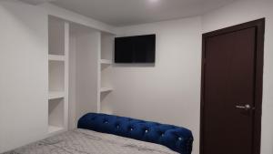 ein Schlafzimmer mit einem blauen Sofa und einem TV in der Unterkunft Departamentos vacacionales in Rosarito