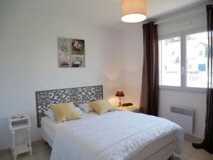 ein Schlafzimmer mit einem weißen Bett und einem Fenster in der Unterkunft Villa Erdeven, 5 pièces, 8 personnes - FR-1-479-14 in Erdeven
