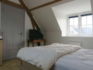 ein weißes Schlafzimmer mit einem Bett und einem Fernseher in der Unterkunft Maison rénovée 100m mer avec WIFI, jardin à Trégastel - FR-1-368-296 in Trégastel