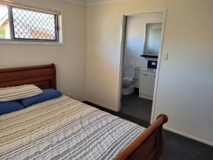 a bedroom with a bed and a bathroom with a toilet at Markwell St Villas in Kingaroy