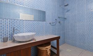 a blue tiled bathroom with a sink and a mirror at The Beach House in Beau Vallon