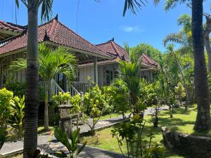 una casa con palmeras delante en The Ocean Sunset Villas Ceningan, en Nusa Lembongan