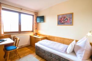 Schlafzimmer mit einem Bett, einem Schreibtisch und einem Fenster in der Unterkunft Hotel Breilerhof in Schladming
