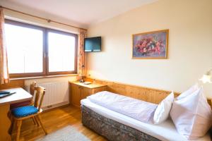 a bedroom with a bed and a desk and a window at Hotel Breilerhof in Schladming