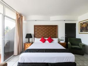 een slaapkamer met een groot bed met rode kussens bij Zona Dorada Suites in Mazatlán