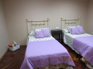 Duas camas num quarto com lençóis e almofadas roxos em RECUNCHO DA LUZ em Arcade