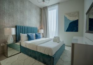 um quarto com uma cama com uma cabeceira azul e uma janela em Nasma Luxury Stays - Harbour Gate Tower 1 em Dubai