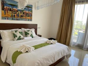 a bedroom with a large bed with white sheets at Minah Bungalows in Nungwi