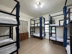 a room with three bunk beds with blue curtains at Nuan Hostel in Xiaoliuqiu