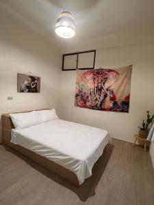 a bedroom with a bed with a painting on the wall at Nuan Hostel in Xiaoliuqiu