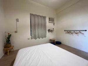 a bedroom with a white bed and a window at Nuan Hostel in Xiaoliuqiu