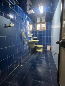 a blue tiled bathroom with a toilet and a sink at Nuan Hostel in Xiaoliuqiu