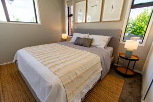 a bedroom with a large bed with two windows at New Boutique Central Sanctuary near Latimer Square in Christchurch