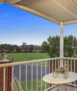 a balcony with a table and a view of a field at Corner Cottage in Dandenong