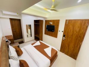 HOTEL BLACK BURN في مومباي: غرفة نوم مع سرير وتلفزيون على الحائط