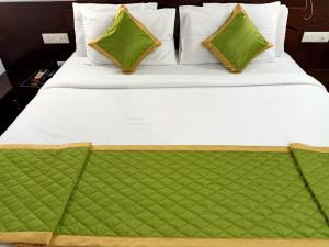 a large bed with white sheets and green pillows at Parco Residency in Tellicherry