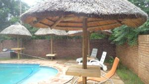 a table and chairs under an umbrella next to a pool at Kadichueni Guest House in Zeerust
