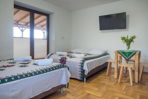 two beds in a room with a tv and a table at Na Kamieńcu in Czarny Dunajec