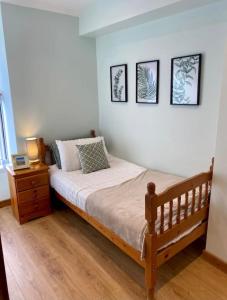 een slaapkamer met een bed en een nachtkastje en foto's aan de muur bij Tegfan Victorian terrace Cottage Snowdonia Llanberis in Llanberis