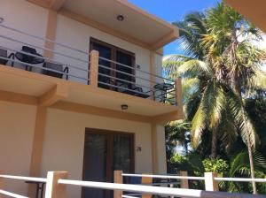 a house with a balcony and a palm tree at Beach Club Condos at Popeyes in Caye Caulker