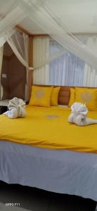 a yellow bed with two towels on top of it at Sekumpul BnB in Singaraja