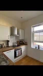 a kitchen with white cabinets and a window at Lovely 1-Bedroom loft apartment in Cardiff
