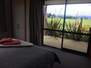 a bedroom with a bed and a large window at Acheron Cottages in Manapouri