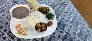 a plate of food with a cup of soup and vegetables at Namaste Bardiya Resort in Bhurkīā