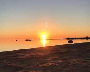 a sunset on the beach with the sun setting at SunBeach Apartment with seaview and sauna in Kalajoki