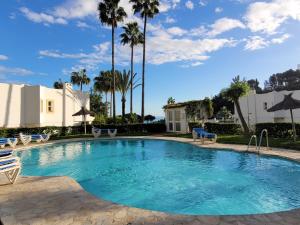 a swimming pool with chairs and palm trees at Secret View Riviera Miraflores in La Cala de Mijas