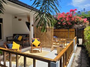 a patio with wooden furniture and flowers on a fence at The Crafty Rooms in Gili Islands