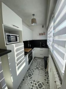 eine kleine Küche mit weißen Schränken und Fliesenboden in der Unterkunft Hirondelle : Appartement privé avec garage in Annecy
