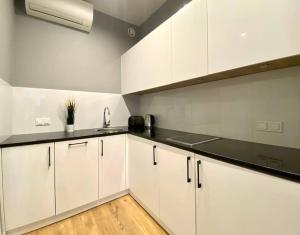 una cocina con armarios blancos y encimeras negras en K22 Slawinska 504 Apart in the Warsaw, en Varsovia