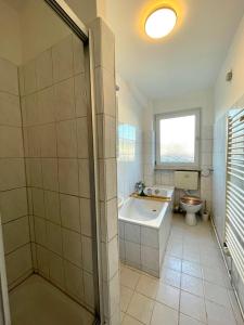 ein Badezimmer mit einer Badewanne, einem WC und einem Waschbecken in der Unterkunft Downtown Apartment by NINJA SPACES - Kingsize-Bett, Küche, Netflix, Terrasse in Wuppertal