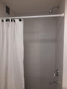 La salle de bains est pourvue d'une douche avec rideau de douche blanc. dans l'établissement Enjoy Departamento Frente al Mar, à Puerto Madryn