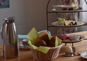 a basket of bread and fruit on a table with a thermos at Hotel Sonnenschein - Spielerei im Sonnenschein in Dahme