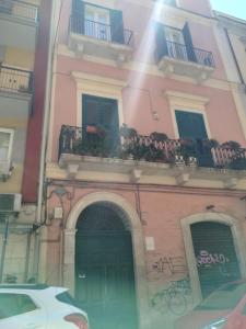 a pink building with a door and a balcony at Benedetto Cairoli Guest House in Bari