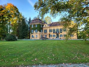 una casa grande con un gran campo de hierba delante de ella en Palais Kneissl, en Burgau