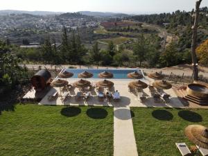 a pool with chairs and umbrellas in a yard at Gordonia Private Hotel in Ma'ale HaHamisha