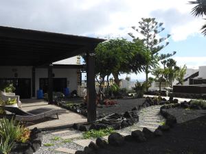 een tuin met rotsen en bomen en een huis bij Habitaciones Doña Cris in Puerto del Carmen